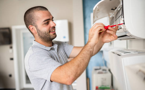 A technician looks at a document while inspecting an air conditioning unit.