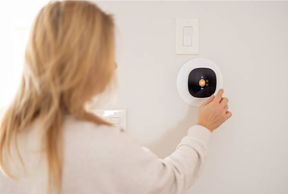 Homeowner Adjusting Wall Mounted Smart Thermostat