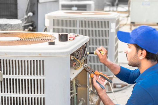 HVAC Technician services an outdoor air conditioning unit.