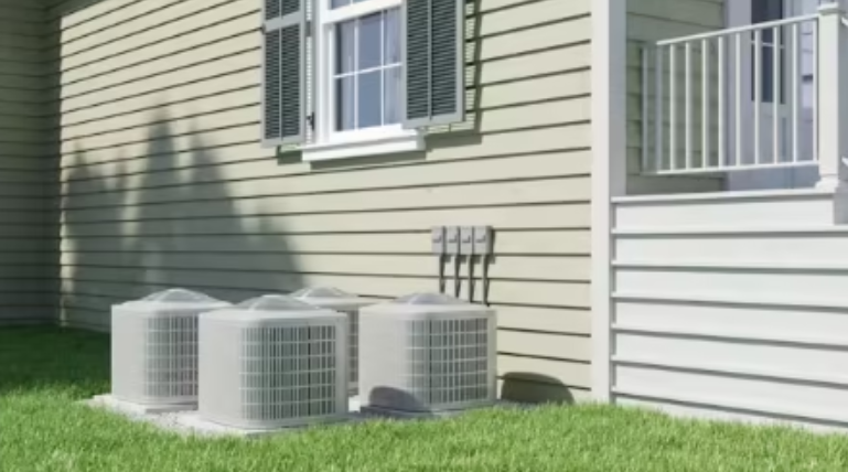 Multiple outdoor air conditioning condenser units installed beside a residential home for cooling system operation.